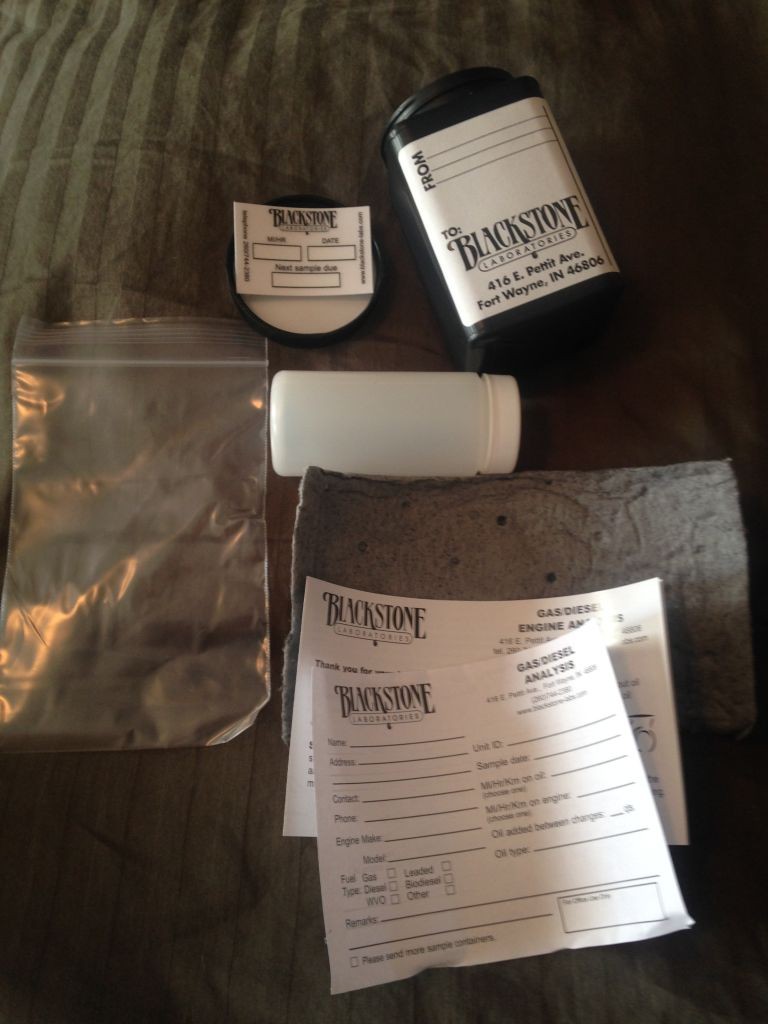 Contents of the oil testing kit: Outer bottle, inner oil sample bottle, ziploc for the inner bottle, absorbent cloth to wrap around inner bottle, report sheet, and window decal 